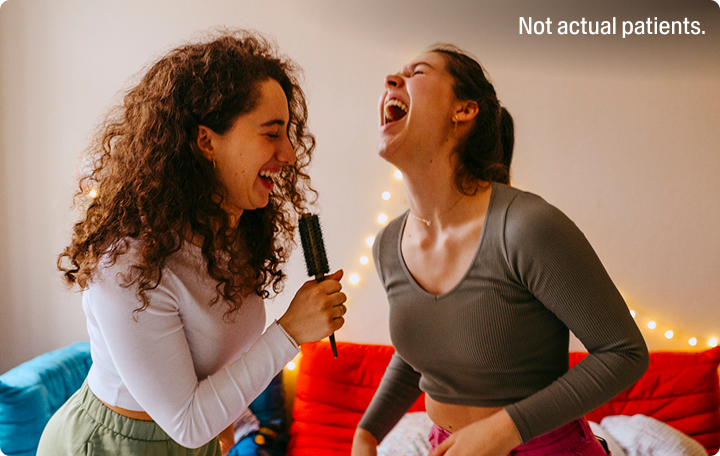 Two women singing into a hairbrush